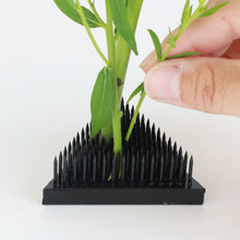 Load image into Gallery viewer, Hand placing a flower stem on the Black Triangle Kenzan