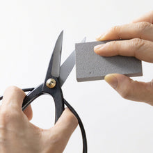 Load image into Gallery viewer, hand cleanign up a bonsai scissors bland with sap eraser